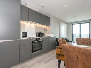 a kitchen with grey cabinets and a table with chairs at Amazing Views in Central Leeds - Pass The Keys in Leeds
