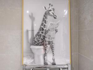 a giraffe standing in a toilet reading a newspaper at Amazing Views in Central Leeds - Pass The Keys in Leeds
