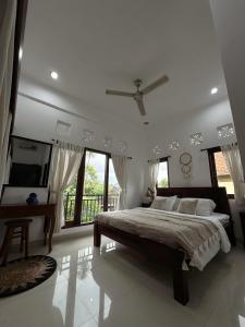 - une chambre blanche avec un grand lit et des fenêtres dans l'établissement The Light House Villa in Ubud, à Ubud
