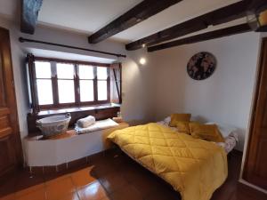 a bedroom with a yellow bed and a window at Le gîte de Latour Bas in Sainte-Énimie