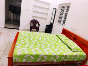 a bedroom with a bed with a green comforter and a chair at Jeevakanthan Home Stay in Alāndurai