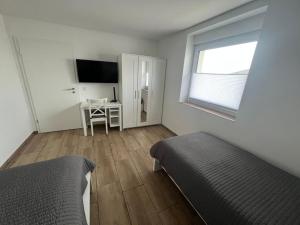 グライフスヴァルトにあるFerienwohnung Miloのベッド2台と机と窓のある寝室