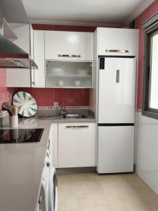 a kitchen with white cabinets and a white refrigerator at La Casa del Muelle in Huelva +6 photos