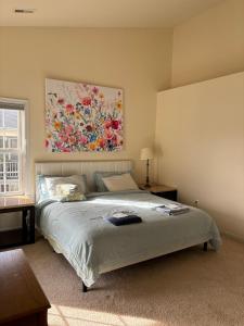 a bedroom with a bed with a painting on the wall at Maple Lawn Gem -sunny townhouse 3 bedrooms in Laurel