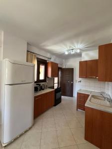 a kitchen with a white refrigerator and wooden cabinets at Penelope's Maisonette in Skala Potamias