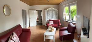 a living room with red couches and a table at Ferienwohnung am Eschenberg in Vinstedt