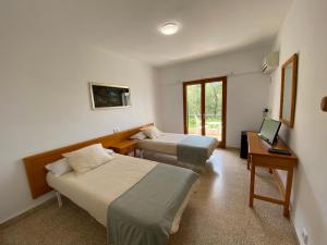 a hotel room with two beds and a television at CH El Quijote in Cala Murada