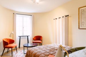 a bedroom with a bed and two chairs and a window at Le Prieuré in Châteauneuf-du-Pape