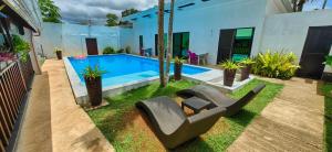 a backyard with a pool and chairs and a house at Jasmin Czechinn in Dauis