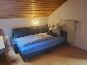 a blue bed in a room with a wooden ceiling at Biohof Dimper - HühnerNest in Saulgrub