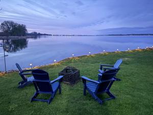 three blue chairs sitting on the grass near a lake at Sun Chaser Bay in Carrying Place