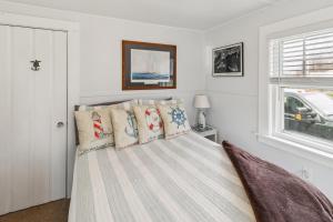 a bedroom with a bed with white walls and a window at Coastal Cottage Retreat Steps from the Beach cottage in Wareham