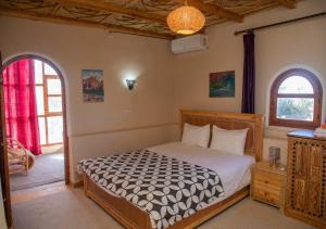 a bedroom with a bed and two windows at Bassatine Skoura in Skoura +93 photos