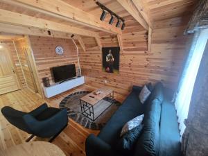 a living room with a blue couch and a tv at Old Story Chalets in Žabljak