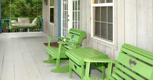 Country Cottage في نيوبورت: شرفة مع كرسيين أخضرين ومقعد