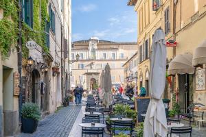 Un callejón con mesas, sillas y sombrillas en una calle de la ciudad. en Julie - Casa del '700, en Castel Gandolfo