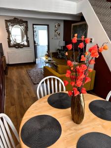 einen Esstisch mit einer Vase mit roten Blumen in der Unterkunft Stylish Uphill Townhouse in Lincoln