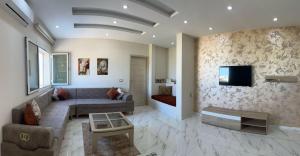 a living room with a couch and a tv on a wall at Maison tnazefti in Djerba