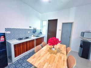 una cucina con tavolo in legno e vaso di fiori di Santorini Vibes Penang - Tasek Gelugor a Kampong Selamat