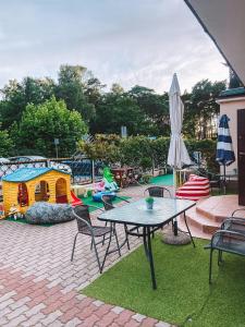 a patio with a table and an umbrella and a playground at Dom na Fali Darlowko in Darlowko