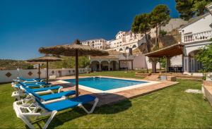 un gruppo di sedie e ombrelloni accanto a una piscina di Villa El Torreón a Casarabonela