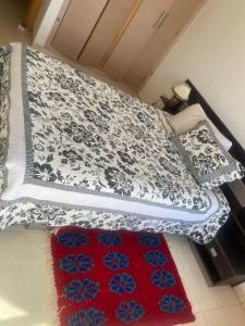 阿加迪尔Adan Beach Apartment的一张铺着蓝白相间毯子和红色地毯的床