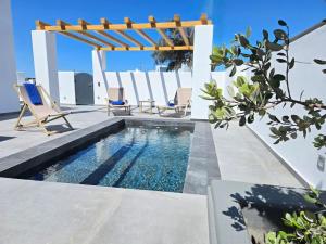 a swimming pool with chairs and a gazebo at Santorini Ethereal Blue Suites in Pyrgos