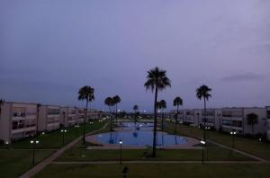 a pool in a park with palm trees and buildings at Ola blanca 1 enjoy in Sidi Rahal