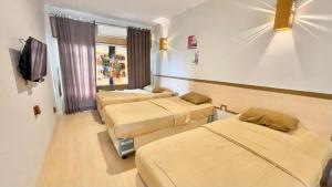 a hospital room with three beds and a tv at The Kanzi Hotel & Village in Cipayung