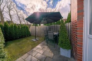 a patio with a table and an umbrella at Aurora Schaar 3 in Wilhelmshaven