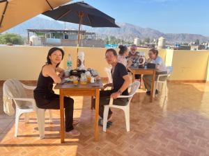 a group of people sitting at a table with an umbrella at HOTEL SAMANAHUASi in Nazca