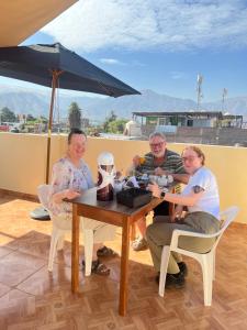 a group of people sitting at a table with an umbrella at HOTEL SAMANAHUASi in Nazca