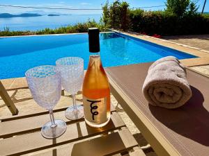 a bottle of wine and two wine glasses next to a swimming pool at The Lookout, boutique villa. in Sivota