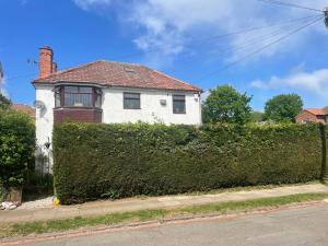 a white house with a hedge in front of it at Camaraderie Guest House in York