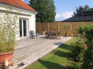 a wooden deck with a table and chairs in a yard at Villa des 4 saisons in Cucq