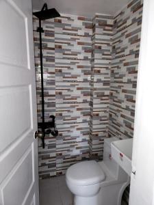 ein Badezimmer mit Toilette und einer Ziegelwand in der Unterkunft Marias couple room in Puerto Galera + 8 Fotos