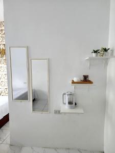 zwei Spiegel an einer weißen Wand mit einer Kaffeemaschine in der Unterkunft Marias couple room in Puerto Galera