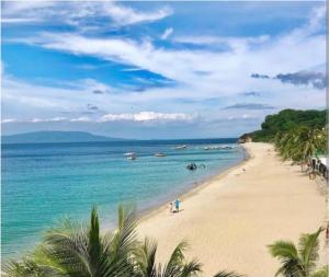 einen Strand mit Menschen und Booten im Wasser in der Unterkunft Marias couple room in Puerto Galera