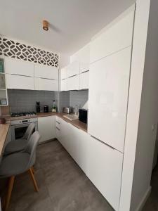 a kitchen with white cabinets and a chair in it at Onix Blue Mamaia Nord in Năvodari