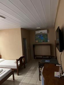 a room with a bed and a table and a tv at Chalé em Parque Aquático - Presidente Figueiredo in Presidente Figueiredo