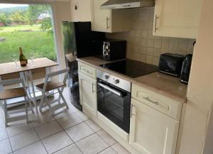 eine Küche mit Tisch und Herd Oberer Backofen in der Unterkunft Riverbank Cottage River Ehan Double Balcony in Egremont