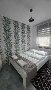 a bedroom with a large bed with a tropical wallpaper at Country House - apartamenty blisko Energylandii in Spytkowice