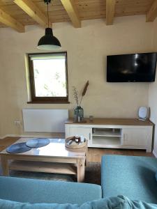 a living room with a table and a tv on the wall at Przystanek Zawóz in Zawóz