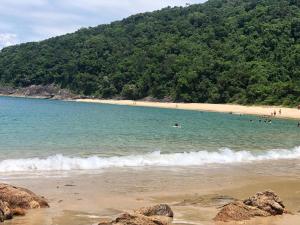 a group of people swimming in the water at a beach at Casas do Luiz Miguel in Caraguatatuba