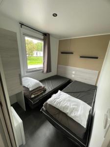 米尼赞海滩KOKUA VACANCES Mobil Homes Résidentiels camping 4 étoiles MIMIZAN PLAGE的有两张床和一扇窗户的小房间