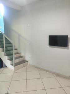 Zimmer mit Treppen und einem TV an der Wand in der Unterkunft Conexão conforto in Vespasiano