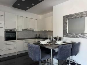 a kitchen with white cabinets and a table with chairs at Apartment Villa Marjanovic in Opatija