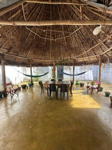 a dining room with a table and chairs under a straw roof at Las Reinas House Rental in Inírida