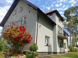 a white house with red flowers in front of it at Dom Gościnny Sówka in Pobierowo