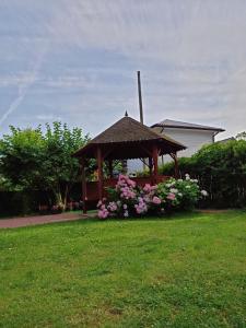 a wooden gazebo with flowers in a yard at Dom Gościnny Sówka in Pobierowo